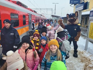 dzieci idące na dworcu przy pociagu w tle maskotka ochrony straży kolei